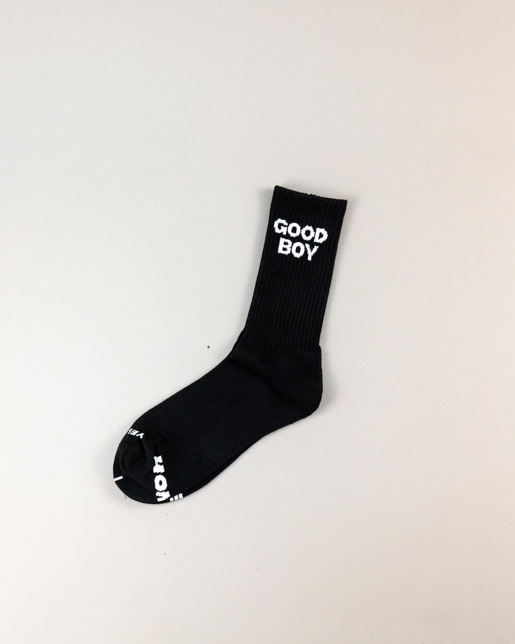 Black sock with 'GOOD BOY' text on a light gray background