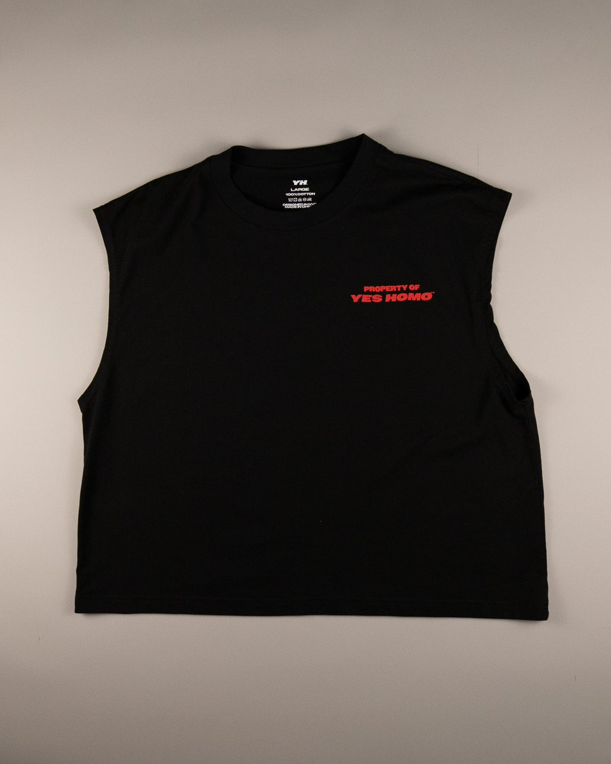 A black sleeveless crop top with a crew neck, featuring a small red and white graphic on the left chest that reads 'PROPERTY OF YES SONGS', laid flat against a neutral gray background.