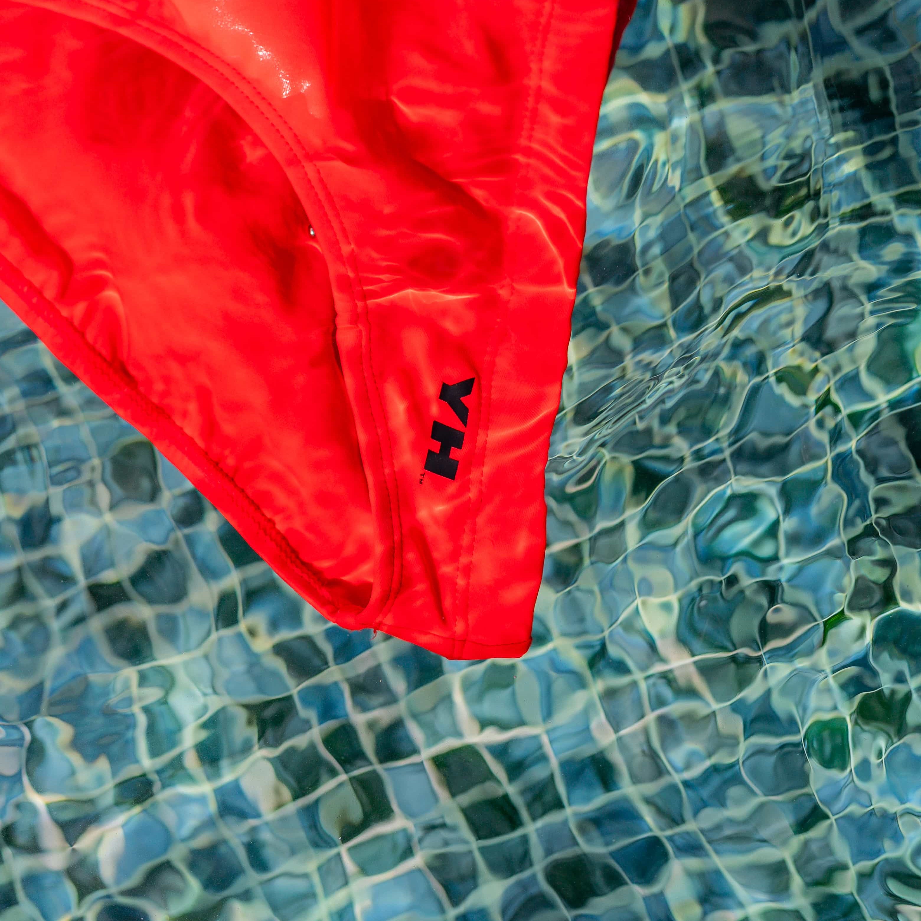 Red swim cap with a brand logo on a textured blue surface